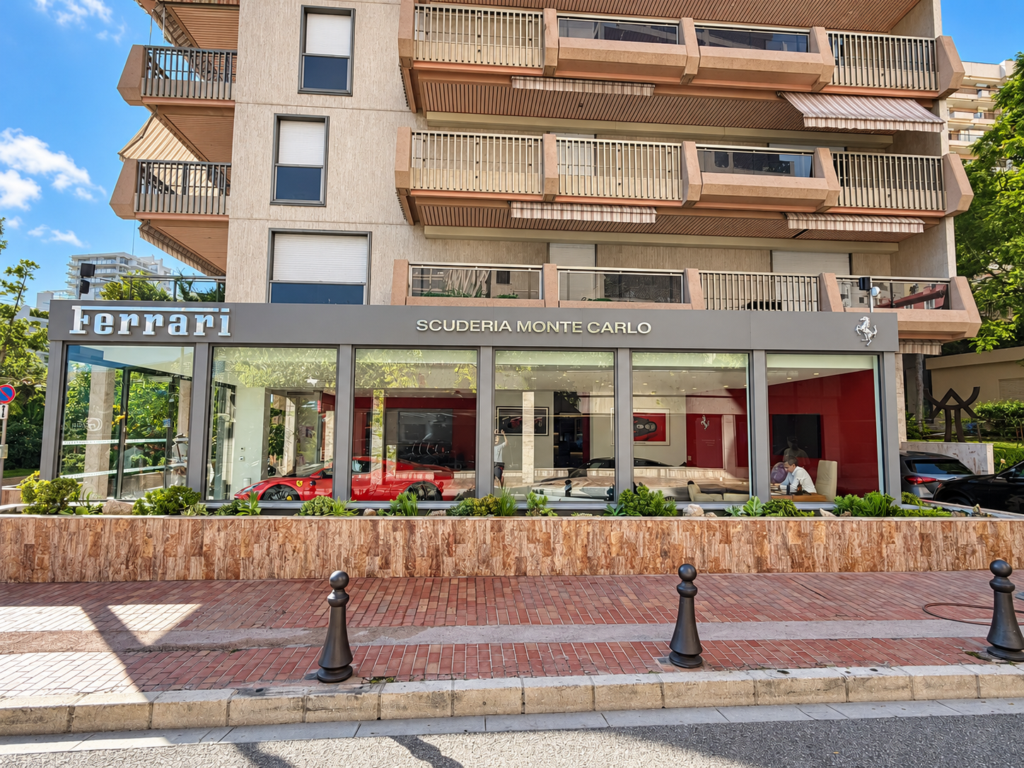 Vue d’ensemble de la jardinière de plantes grasses au pied de la résidence La Réserve à Monaco, devant les vitrines.